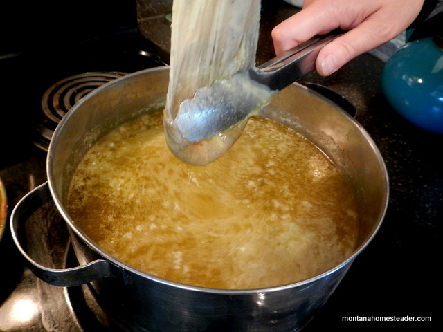Squeezing melted beeswax out of cheesecloth when rendering beeswax from honeycomb