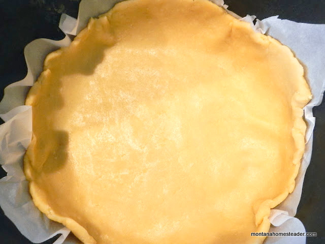 rolling out a pie crust on parchment paper to bake a pie in a dutch oven