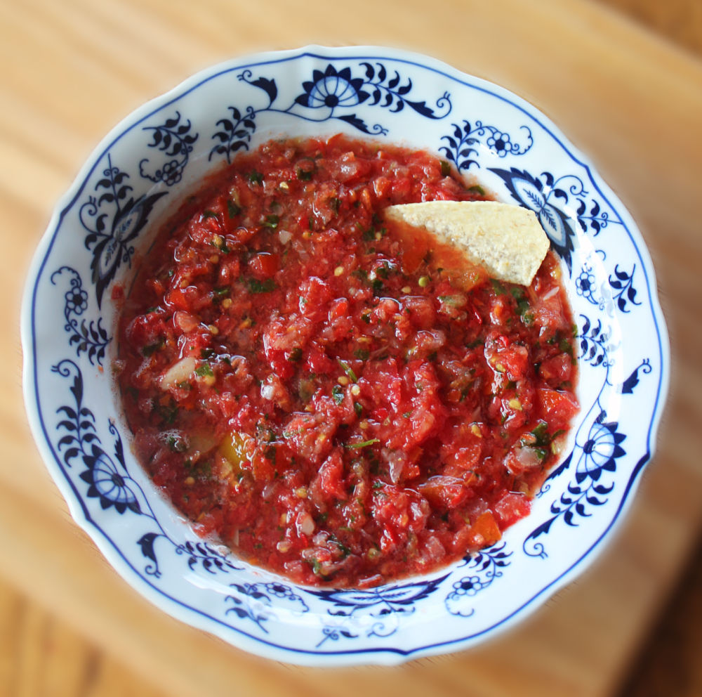 How to make garden fresh salsa recipe bowl of homemade homegrown salsa chunky tomatoes peppers onions cilantro garlic in blue white antique china bowl with tortilla chip scooping salsa