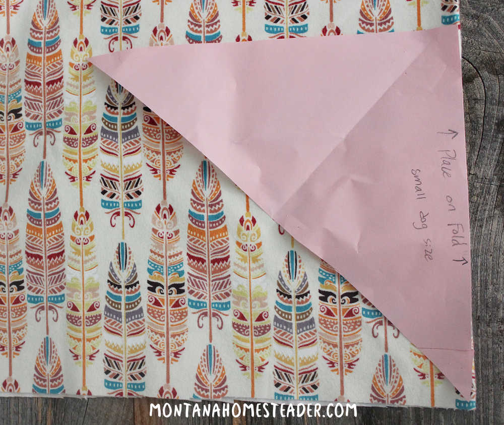 How to make a simple dog bandana how to make a free pattern for a DIY dog bandana paper pattern lying on colorful fabric ready to be cut out